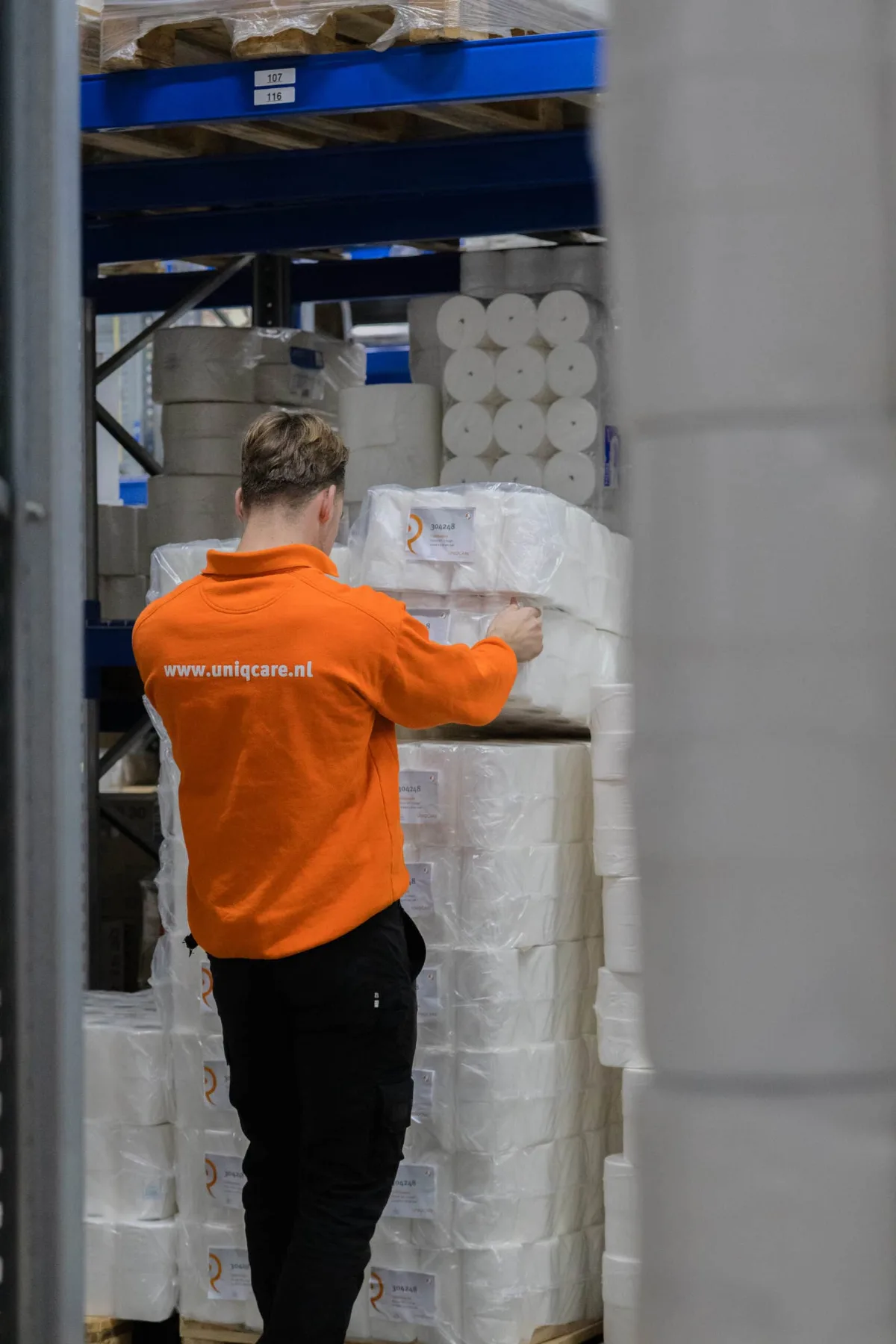Een medewerker van Uniqcare zet toiletrollen klaar in het magazijn