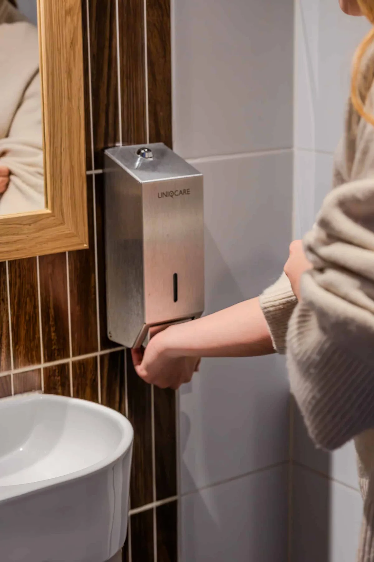 Een hand bij een roestvrijstalen zeepdispenser