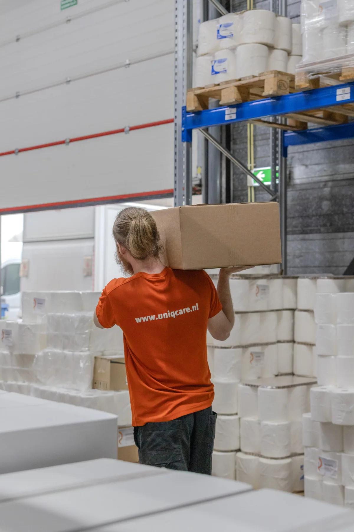 Een medewerker pakt een doos uit het magazijnrek